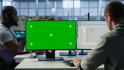 Engineer in server hub using green screen PC to repair equipment storing datasets. Professional...