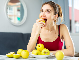 Obraz premium Portrait of a happy woman with apples at the table in the room at home. Diet and weight loss concept