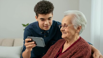 Young man teaches elderly woman smartphone skills with fun and laughter at home
