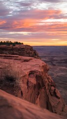 A stunning landscape features a sandstone cliff, a beautiful sunset sky over the ocean, with gorgeous light