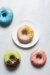 Overhead view of colorful glazed donuts on a white countertop, top view of homemade pastel doughnuts, process of making glazed doughnuts