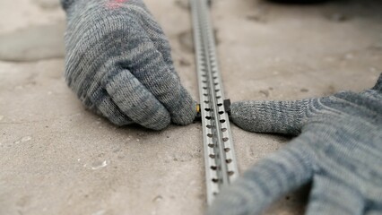 Construction worker is installing a tile leveling system on a metal profile to ensure even tile...