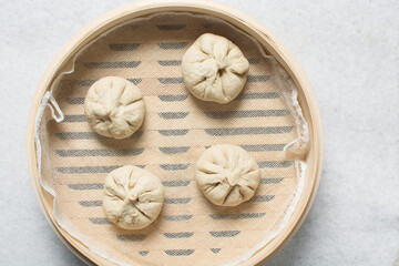 Overhead view of chicken bao in a bamboo steamer, top view of baozi in a steamer, process of making homemade baozi
