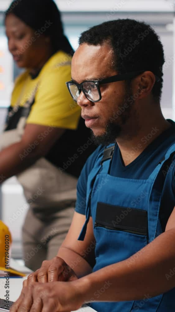 Poster vertical video black engineer implements automation logic in solar factory software, working on manu