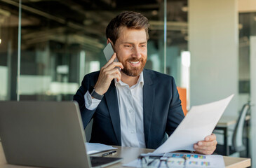Corporate communication. Happy male manager working remotely, reading financial document and...