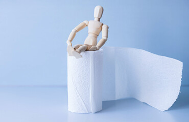 Wooden figure sit on a roll of toilet paper.