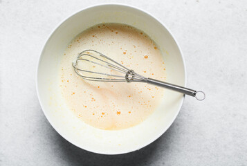 Whisking eggs and sugar together until pale, mixing eggs and sugar by hand, process of making a cake