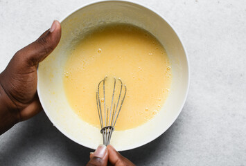 Whisking eggs and sugar together until pale, mixing eggs and sugar by hand, process of making a cake