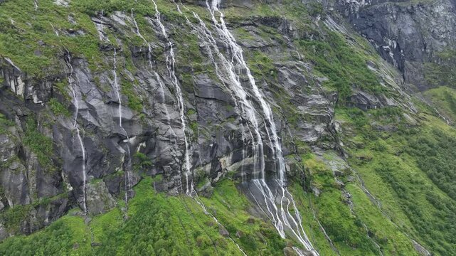 Waterfalls cascade down the rocky cliffs of Vikagjolet Fossen in Loen, Norway lush landscape
