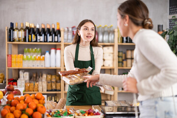 Female seller offers to buy nougat to woman in interior of a grocery supermarket
