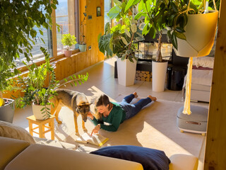 Woman lies on the floor and shows her curious dog a page in book she is reading. Young dog owner...