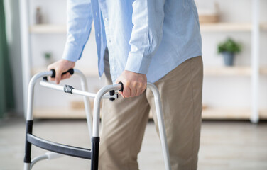 Cropped view of elderly man walking with frame at home, closeup. Unrecognizable senior male using...