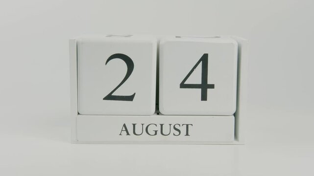 A hand flips a wooden calendar from August 24th to August 25th on a white background, symbolizing the transition to a new day