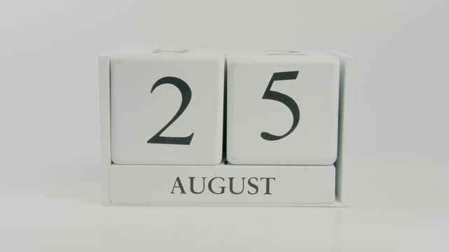 A hand flips a wooden calendar from August 25th to August 26th on a white background, marking the passage of time and transition to a new day