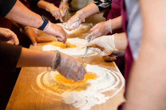 Hands mixing eggs and flour in cooking class.