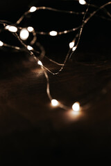 garlands Lights on a Wooden Surface.warm lights garland on brown wooden background. Cozy winter holidays atmosphere