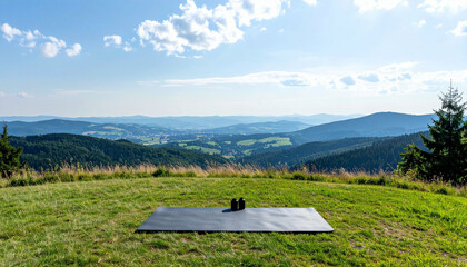 Outdoor workout setting with mat and weights on hilltop overlooking rolling hills & distant town