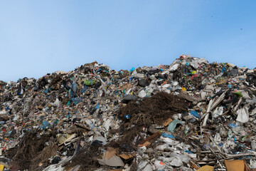 Landfill Site with Large Heap of Discarded Trash and Waste Materials Against Clear Blue Sky, Showing Environmental Issues