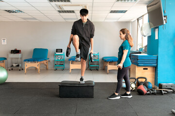 Female therapist monitoring rehabilitation exercise with weights