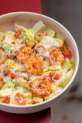 Caesar Salad with Grilled Shrimp, Croutons and Parmesan.
Fresh Caesar salad with grilled shrimp, cherry tomatoes, crunchy croutons and shredded Parmesan in a white bowl.