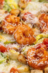 Caesar Salad with Grilled Shrimp, Croutons and Parmesan.
Fresh Caesar salad with grilled shrimp, cherry tomatoes, crunchy croutons and shredded Parmesan in a white bowl.