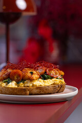 Open Sandwich with Scrambled Eggs, Shrimp and Chili Threads.
Gourmet toast topped with scrambled eggs, sautéed shrimp, spinach and red chili threads, served on a pastel plate.