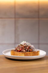 Beef Tartare Toast with Pickled Onions and Chives.
Open-faced sandwich topped with finely chopped beef tartare, pickled red onion and fresh chives on toasted bread.