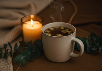 Hot tea cup with candle and eucalyptus leaves.