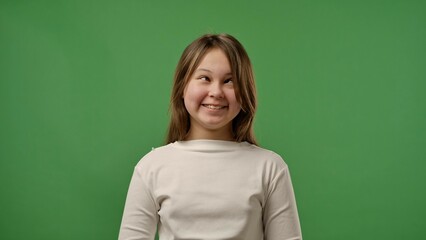 Teenage girl posing at camera smiling making funny faces and grimaces, positive expression, isolated on chroma key green screen studio background mockup.