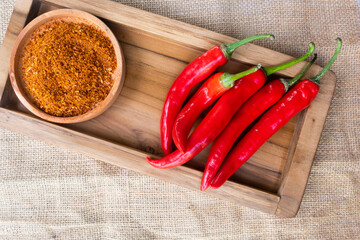 powder and fresh red chilies on a wooden tray and burlap cloth
