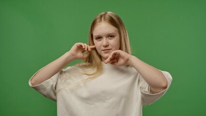 Teenage girl posing at camera smiling, acting like super model, positive expression, isolated on chroma key green screen studio background mockup.