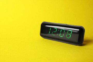 Digital alarm clock showing 12:08 o'clock on yellow background, space for text