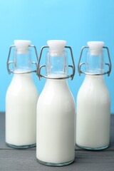 Fresh milk on wooden table against light blue background