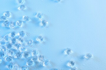 Cubes of clear ice on light blue background, flat lay. Space for text