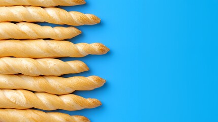 Close up of golden baked breadsticks on blue background showcasing texture and form perfect for food photography or culinary themes with ample copy space