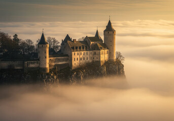 Fototapeta premium Castle shrouded in fog atop misty mountains.