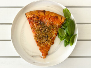 A Slice of Pizza with Sausage, Garlic . Spice, , Herbs and a Side Of Basil. 