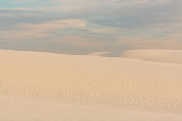 Golden ripples of white sand dunes under pastel evening sky
