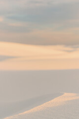 Abstract view of sunlit sand dune with soft pastel sky above with top copy space
