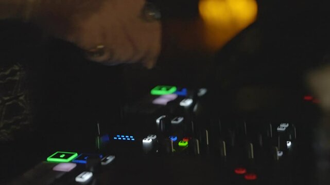 Close-Up of DJ Adjusting Mixer Knobs During Live Performance