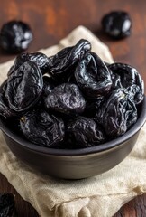 Fresh and Dried Plums in Black Bowl on Wooden Table with Natural Textures and Earthy Tones for Healthy Eating and Culinary Uses in Varied Dishes