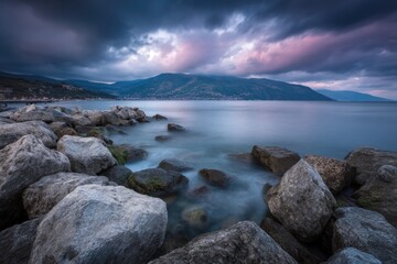 Obraz premium Dramatic Skies Over Rocky Shores A Serene Lake Evening with Mountains Backdrop