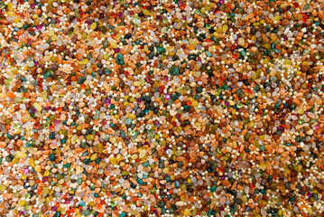 Vivid surface full of mixed gems, pearls, and beads. Decorative stones in rich hues create a shiny and artistic natural background