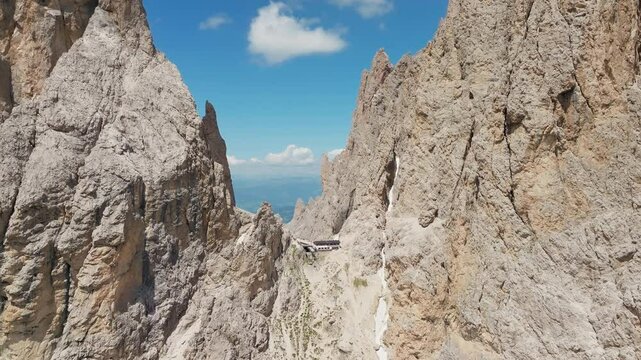 Slow panning drone shot of Toni Demetz Hut perched dramatically in the Forcella del Sassolungo, Dolomites, Italy