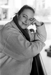 Smiling woman leaning on railing in monochrome analog photo