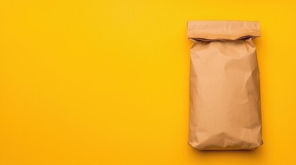Brown paper bag on a bright yellow background, creating a minimalist and eco-friendly visual.