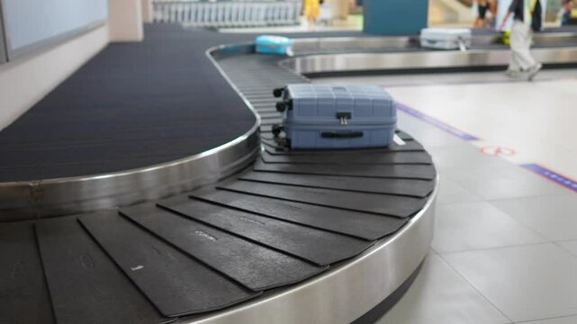 Suitcases travel along airport baggage carousel while man identifies and lifts luggage. Travelers waiting moving bags, flight arrivals continue, tourism flow, luggage handling, post journey reunions