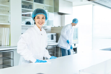 厨房を清掃する衛生白衣を着た男女スタッフ