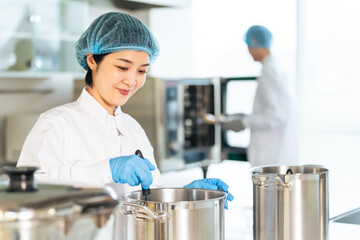厨房で大鍋で調理する衛生白衣を着た女性調理師　給食センター　給食室