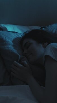 Vertical video. Night rest. Peaceful sleep. Relaxed calm happy woman enjoying dreaming on soft comfortable soft pillow in bed in dark home bedroom.